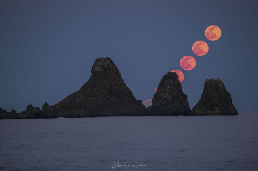 La luna sorge sopra i Faraglioni di Aci Trezza